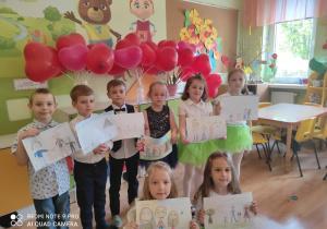 Dzieci z rysunkami członków swojej rodziny.